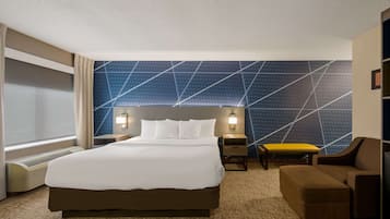 A hotel room with a large bed, two bedside tables with lamps, a chair, and a patterned wall.