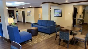 A hotel lobby with a blue sofa, a round coffee table, and patterned chairs. - Comfort Inn Fayetteville I-95 (Fayetteville)