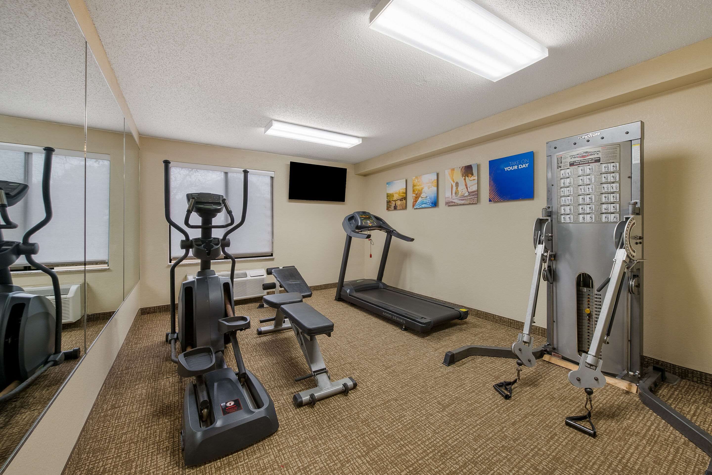 A gym with exercise equipment including treadmills, elliptical machines, and weight machines.