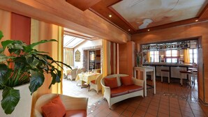 Una habitación amplia con comedor, bar y zona de estar con una planta grande.