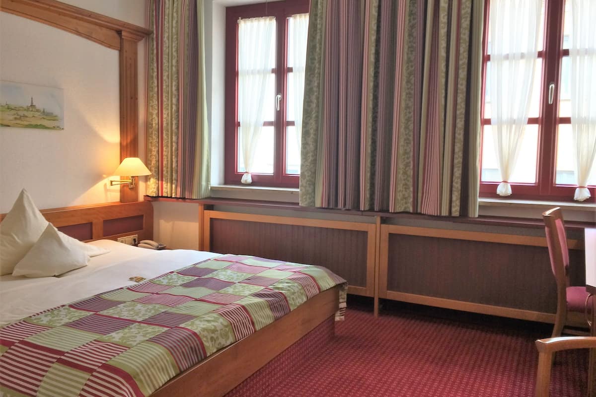Une chambre d’hôtel avec un lit, un bureau et une chaise.