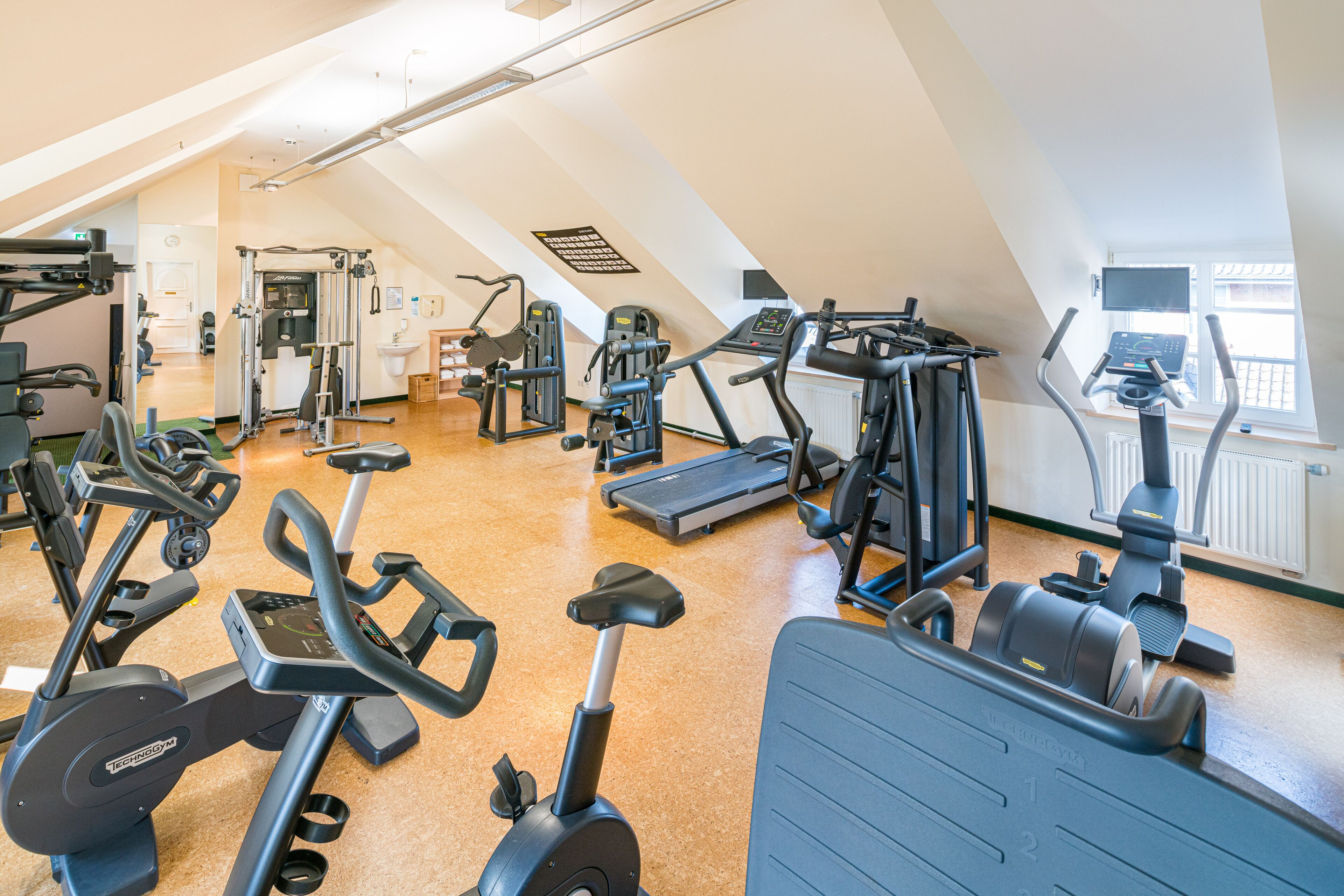 A gym with various exercise equipment, including treadmills, elliptical machines, and weight machines.