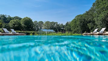 Una piscina techada, una piscina al aire libre, sombrillas