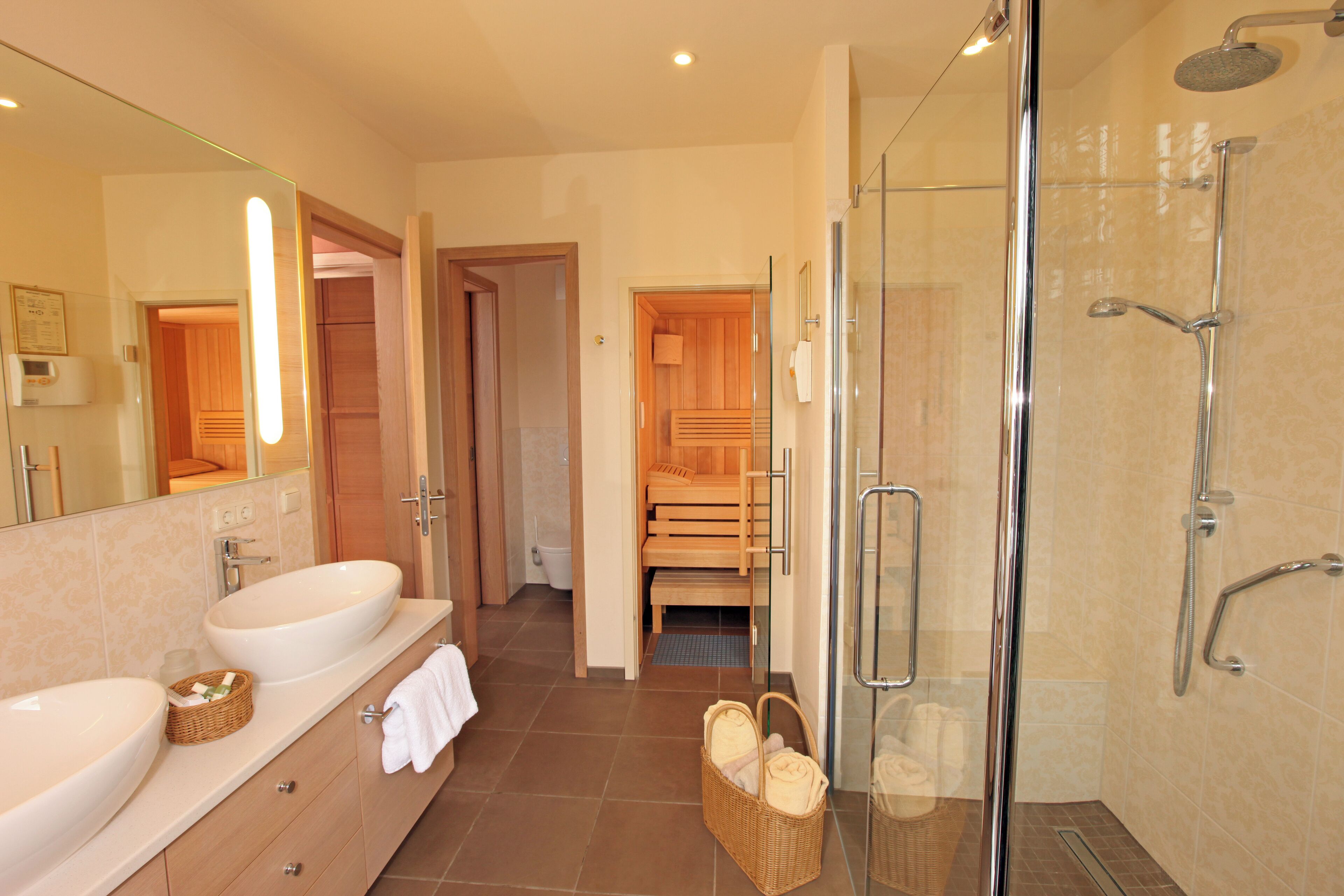 Ein modernes Badezimmer mit einer gläsernen Dusche, einem großen Waschbecken und einer Holzbank im Hintergrund.