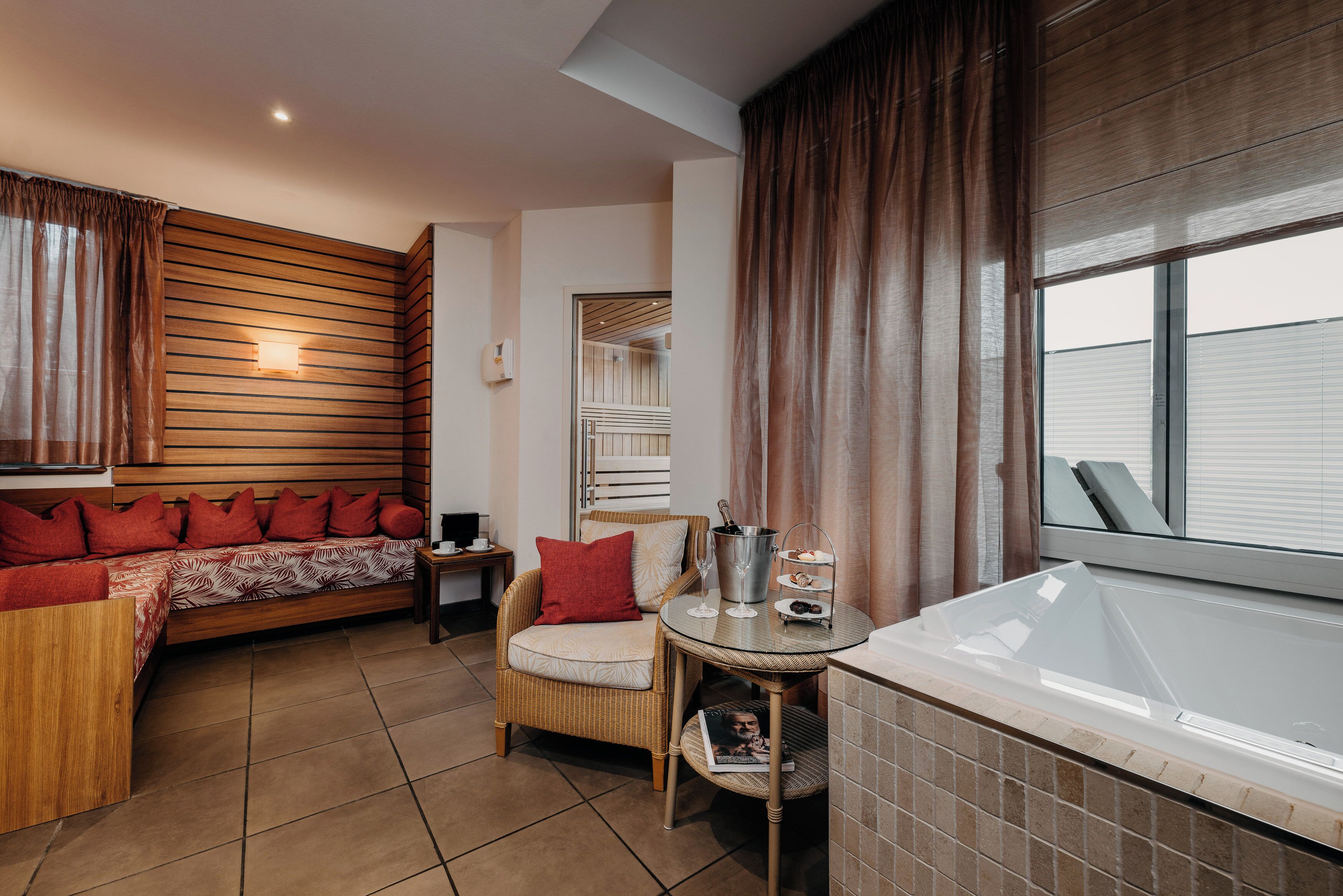 A cozy room with a wooden sofa, a wicker chair, a small table with a tray, and a bathtub.
