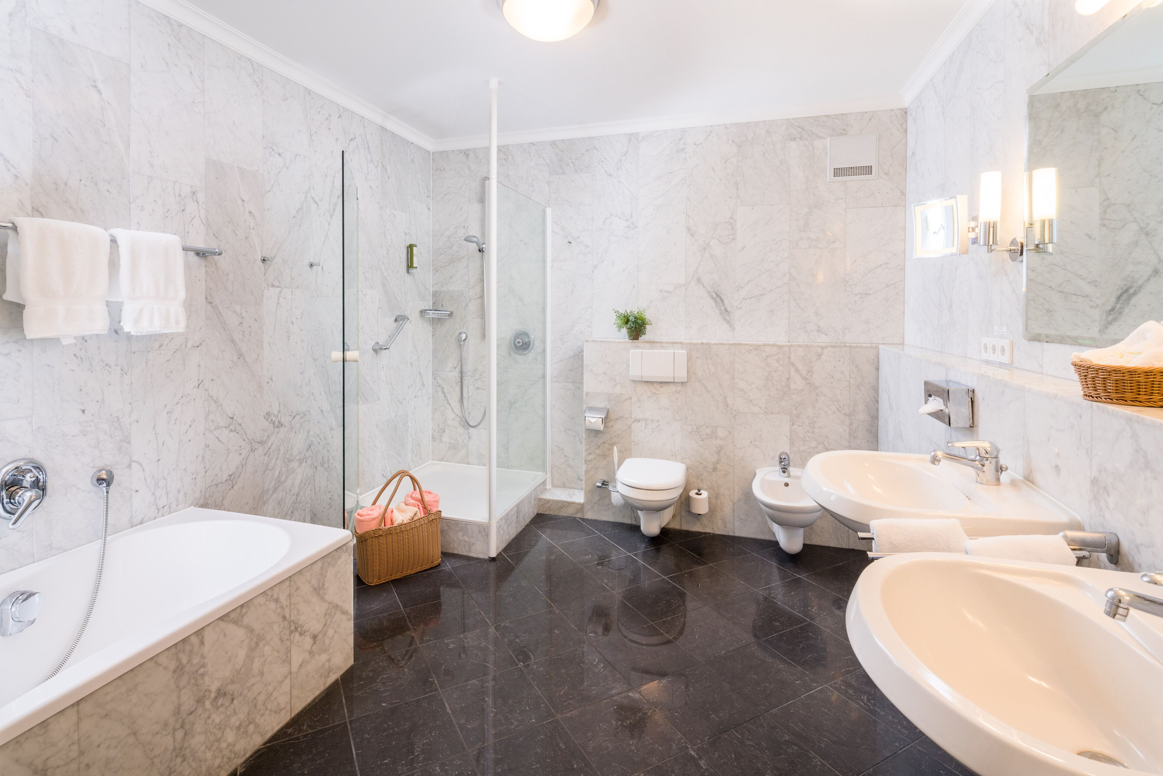 A modern bathroom with a bathtub, a shower, a toilet, and two sinks.