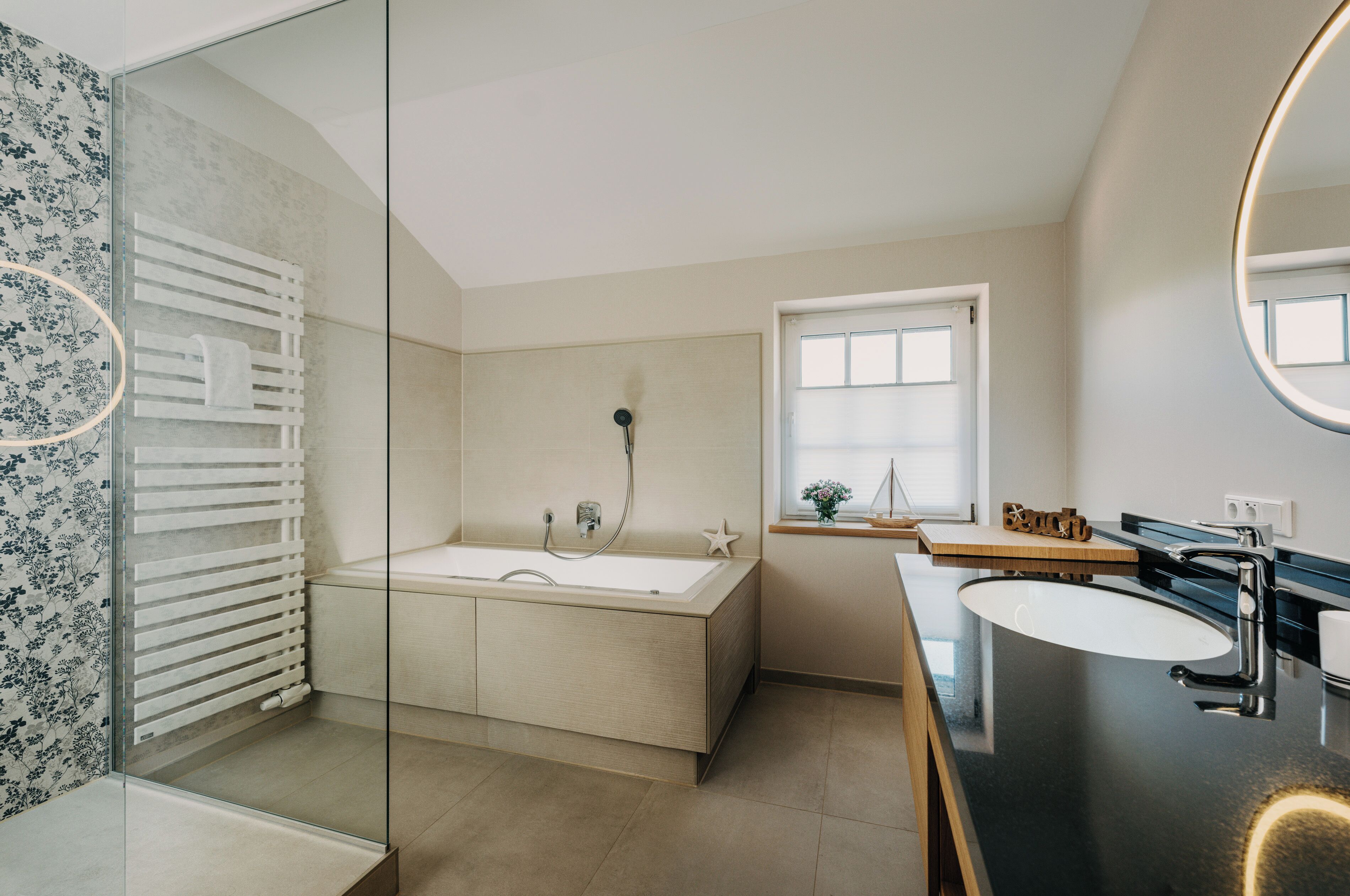 Un baño moderno con una bañera independiente, un tocador con lavabo y un espejo grande.
