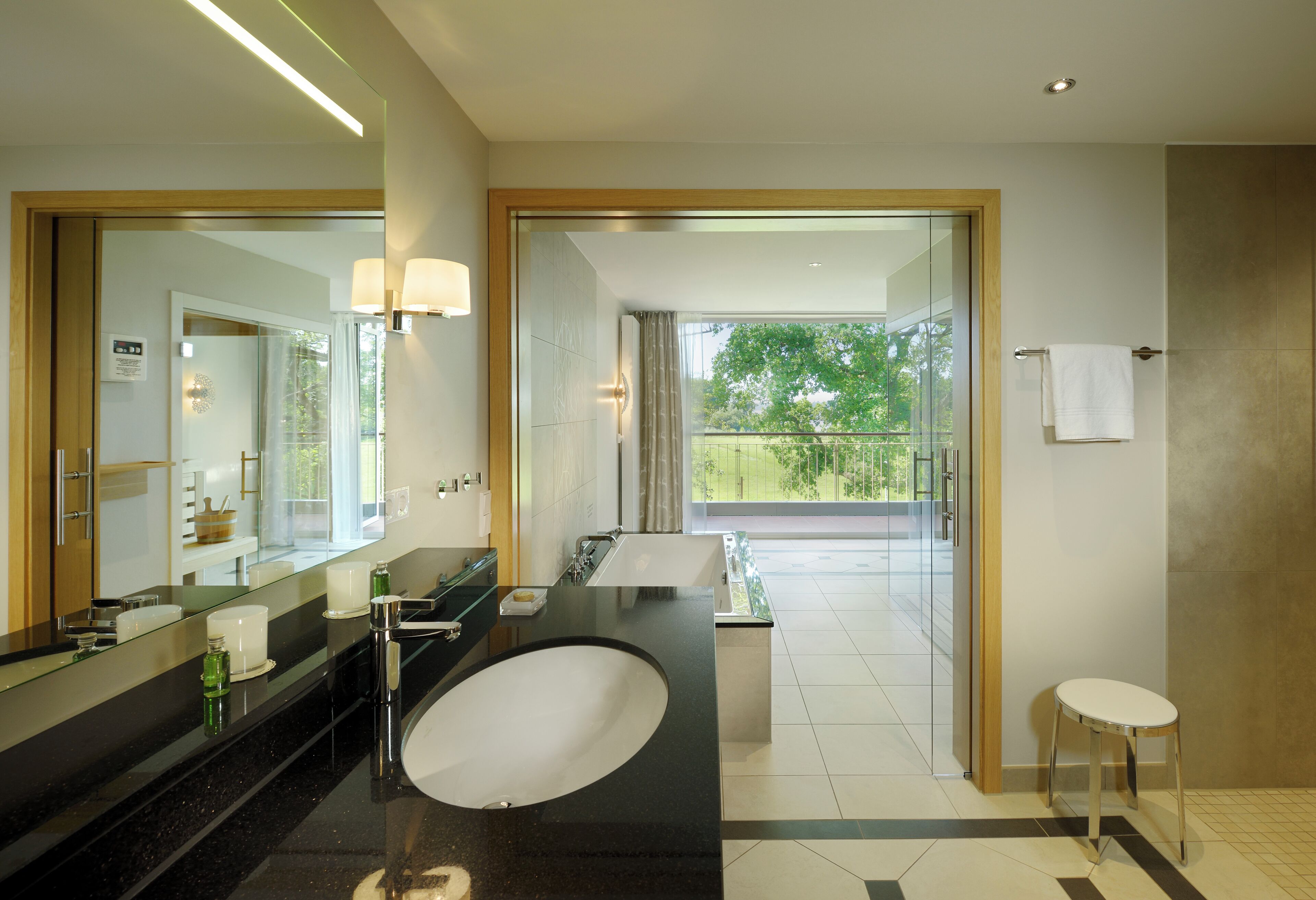 A modern bathroom with a large mirror, black countertop, and a round sink.