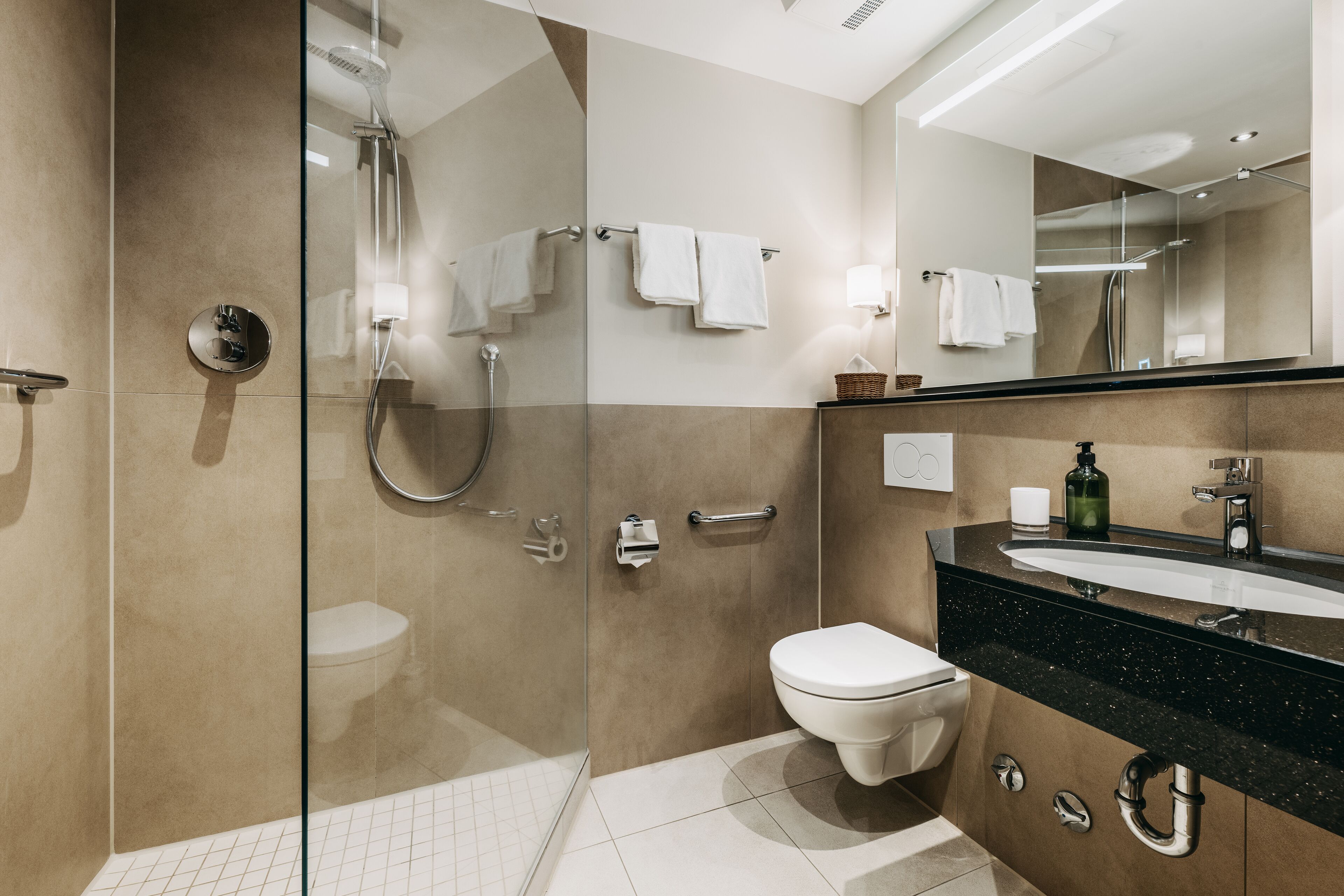 A modern bathroom with a glass-enclosed shower, a toilet, a sink with a black countertop, and a mirror above the sink.