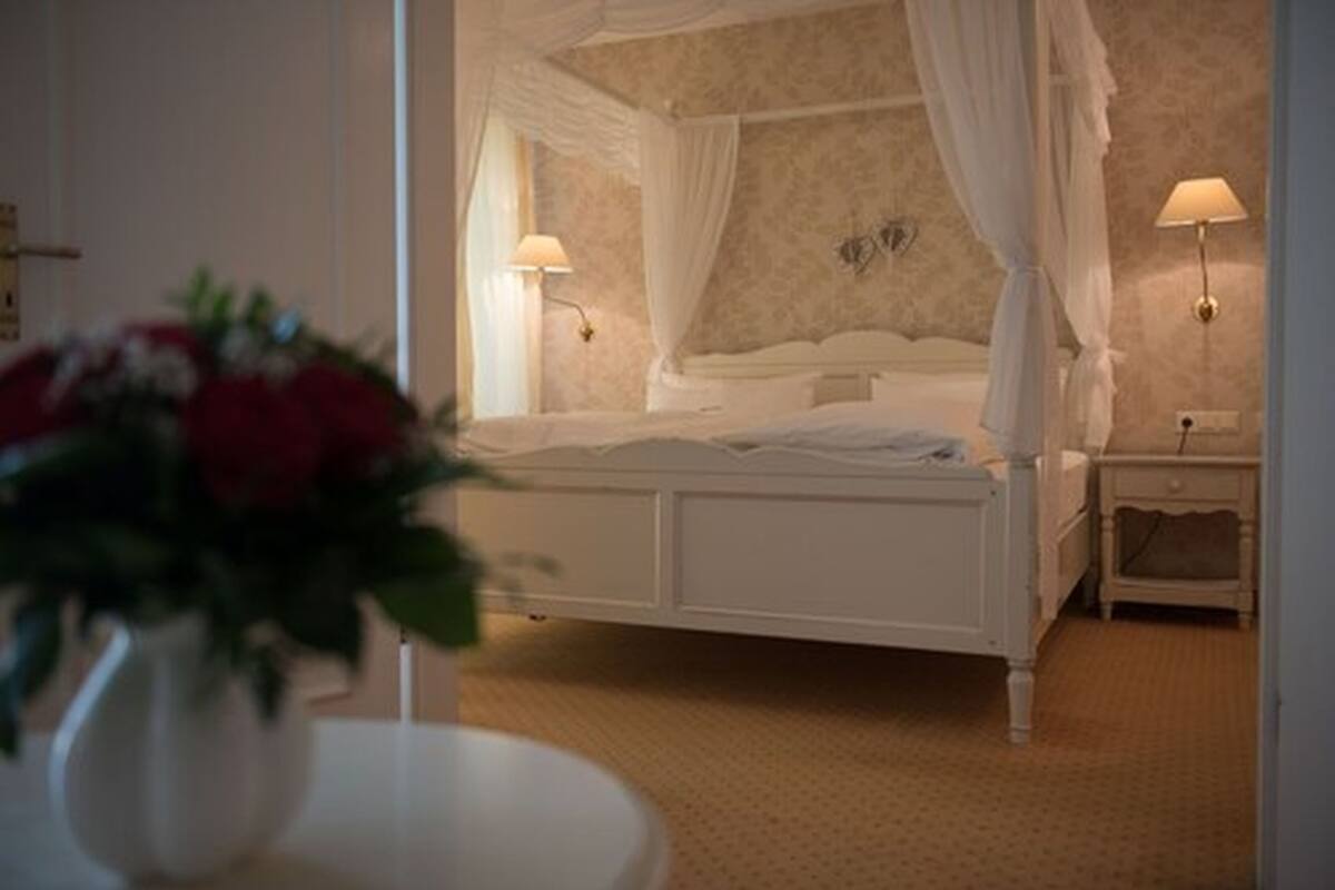 Een slaapkamer met een hemelbed, een nachtkastje en een bedtafel.