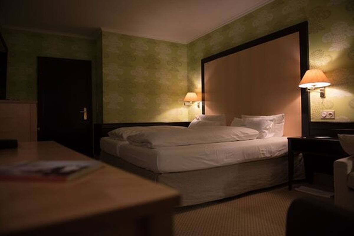 Een hotelkamer met een eenpersoonsbed, twee bedlampen, een nachtkastje en een bureau.