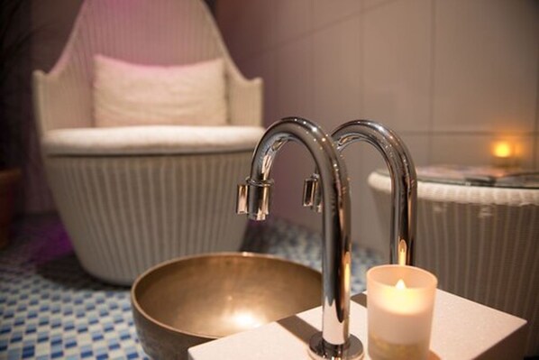 A bathroom with a bathtub, a sink, and a candle. - Romantik Hotel Boesehof (Geestland)