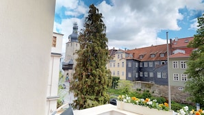 A view of a street with historic buildings, a tall tree, and a flower bed. - DORMERO Hotel Coburg (Coburg)
