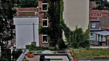 A rooftop terrace with potted plants, outdoor seating, and a view of surrounding buildings.