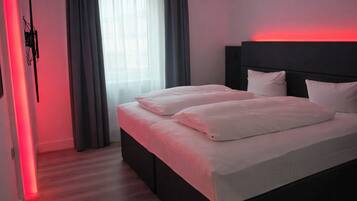 Camera d'albergo moderna con un letto grande, una testiera e una luce rossa d'ambiente.