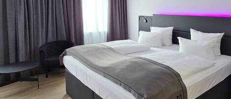 A modern hotel room with a large bed, a desk, and a chair.