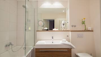 A modern bathroom with a glass-enclosed shower, a vanity with a mirror, and a toilet.
