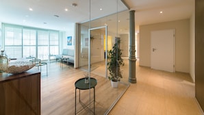 A modern hotel lobby with a glass partition, wooden flooring, and a seating area with tables and chairs. - DORMERO Hotel Coburg (Coburg)