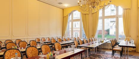 A conference room with long tables, chairs, and a chandelier.