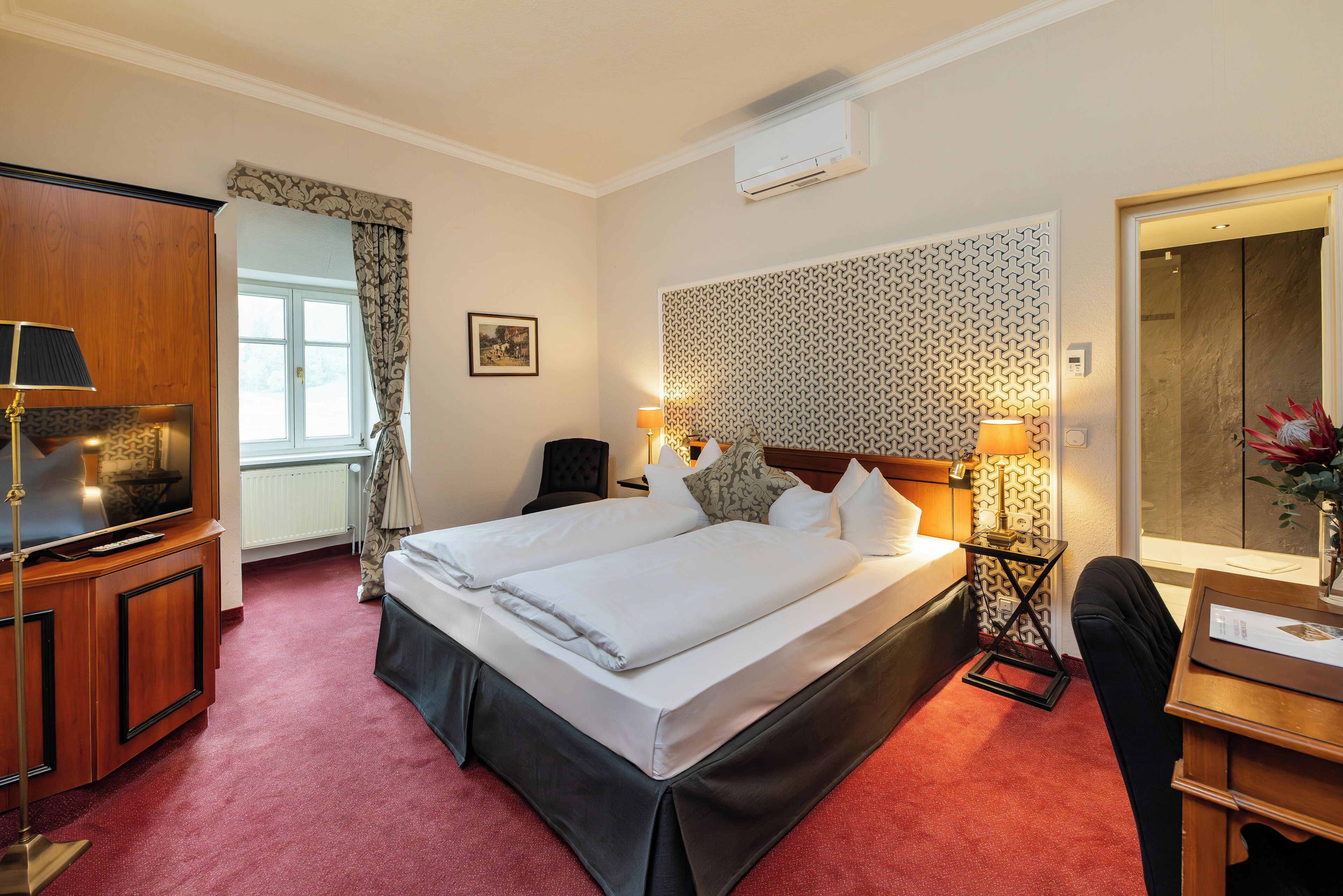 Ein Hotelzimmer mit einem großen Bett, einem Schreibtisch mit Stuhl, einem Fernseher und einem Spiegel.