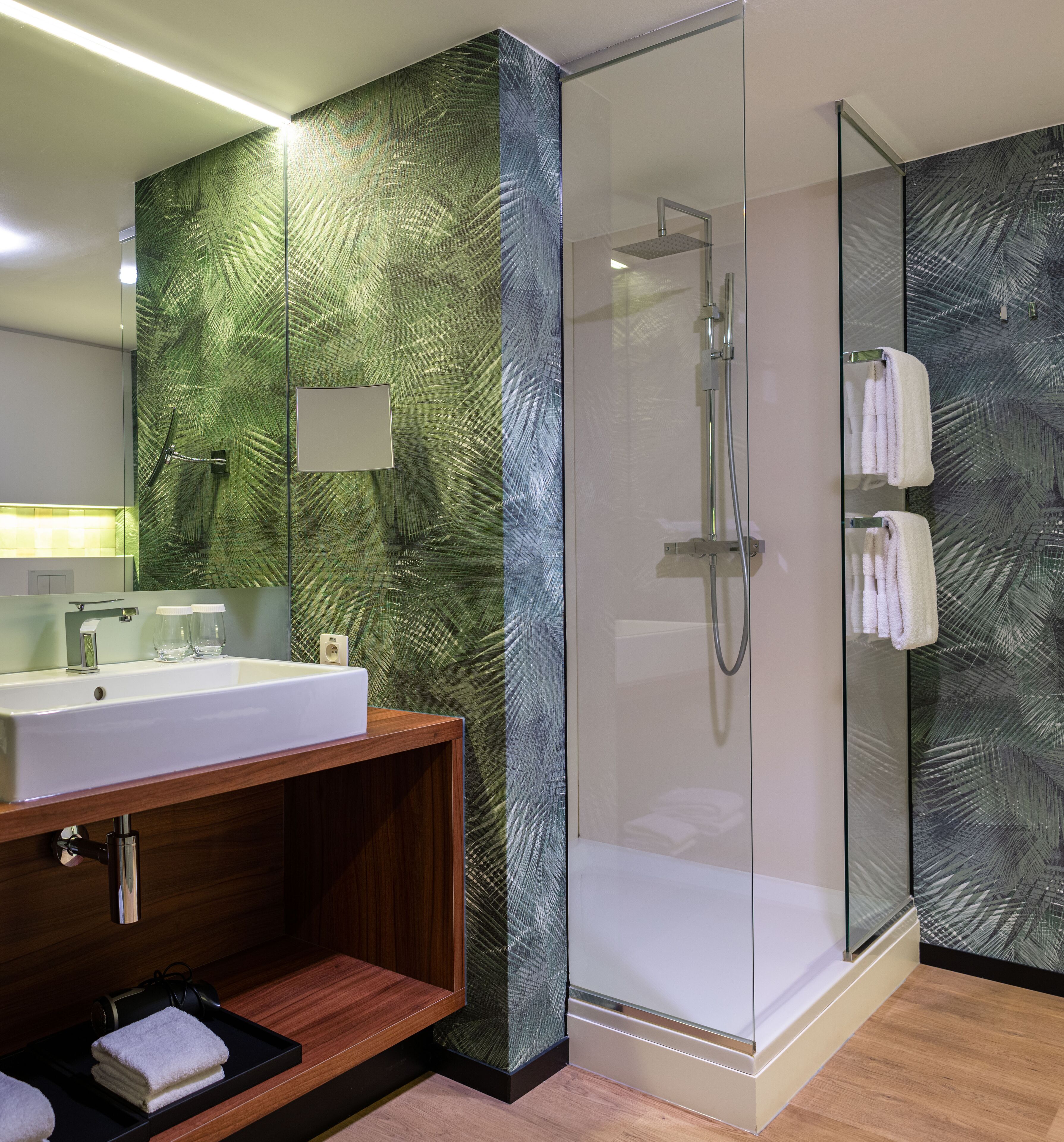 Une salle de bain moderne avec une douche à parois de verre, un meuble-lavabo en bois et un grand miroir.