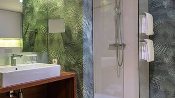 Une salle de bain moderne avec une douche à parois de verre, un meuble-lavabo en bois et un grand miroir.