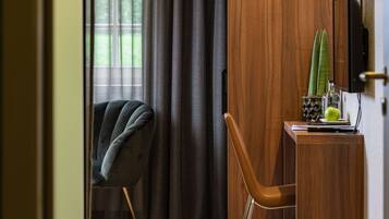 A modern room with a wooden desk, a chair, a television, and a window with curtains.