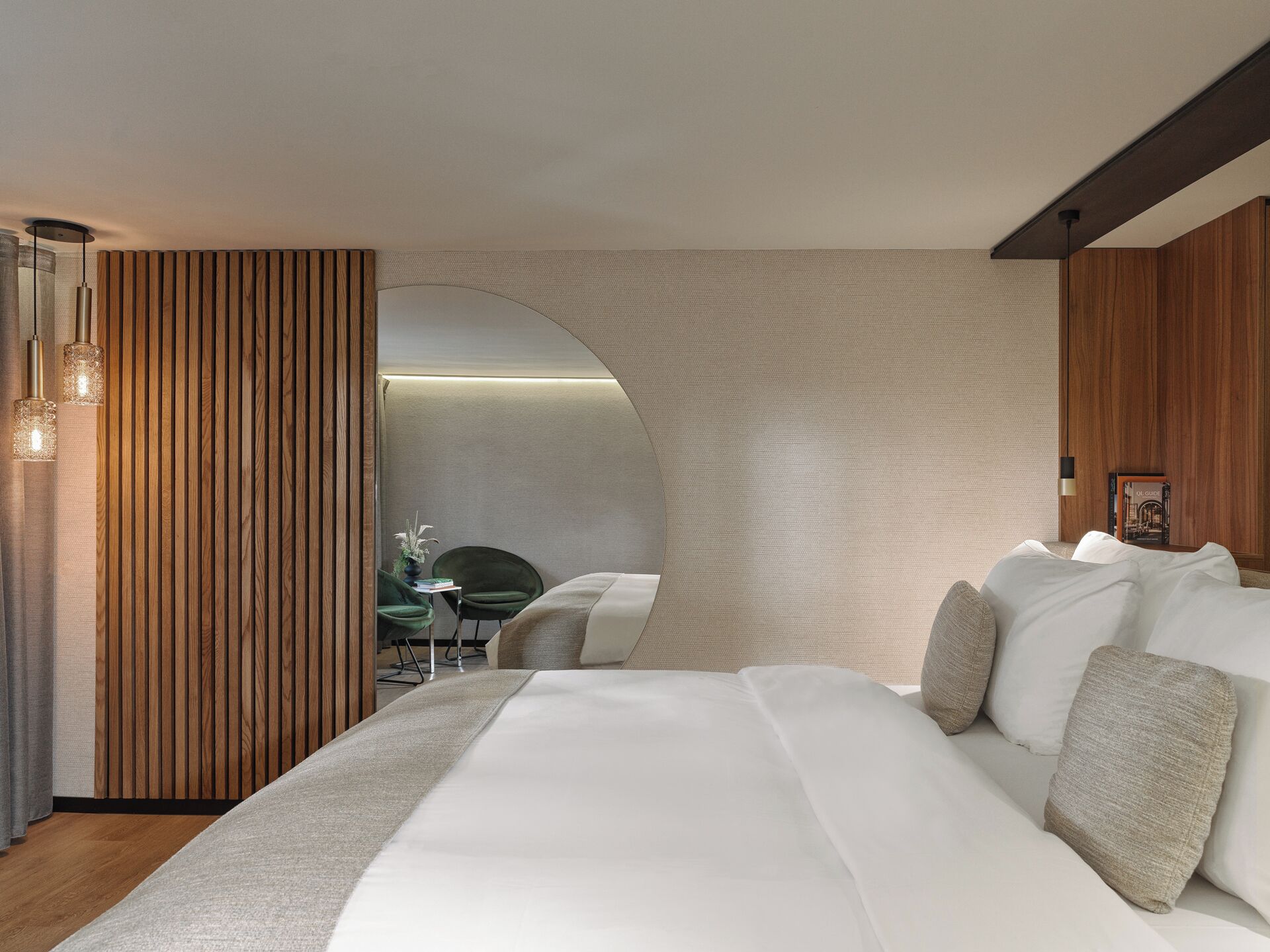 Een moderne hotelkamer met een groot bed, een wand van houten panelen en uitzicht op een eetruimte.