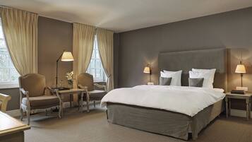 A hotel room with a large bed, two bedside tables with lamps, a chair, and a desk with a lamp.