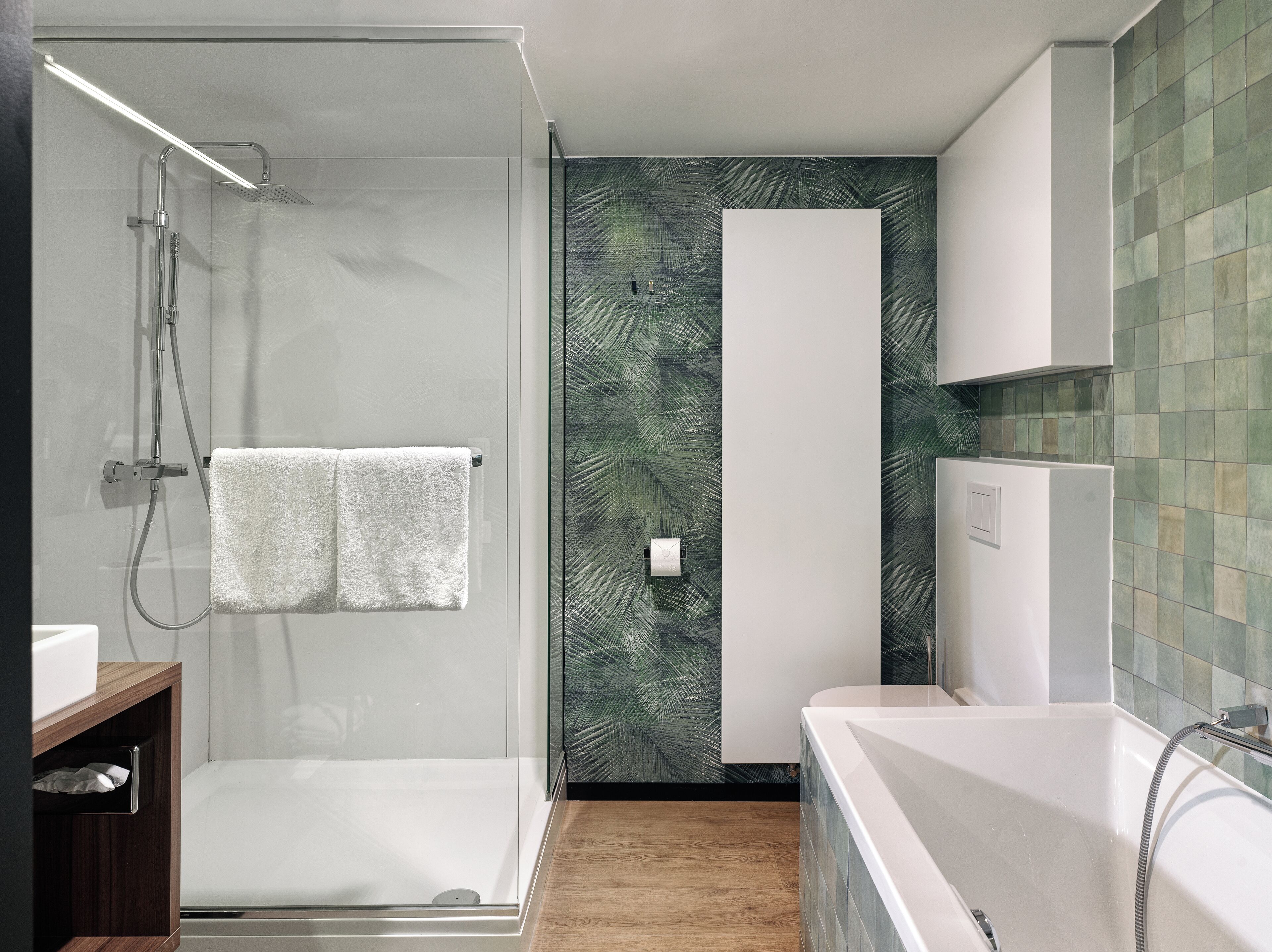 Een moderne badkamer met een glazen douchecabine, een witte badkuip en een houten wastafelmeubel.