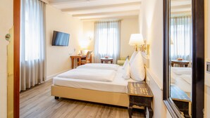 A hotel room with a bed, bedside tables, a TV, and a mirror.
