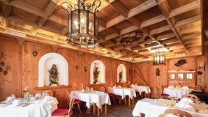 A restaurant with wooden walls and ceiling, multiple tables set for dining, and a chandelier.