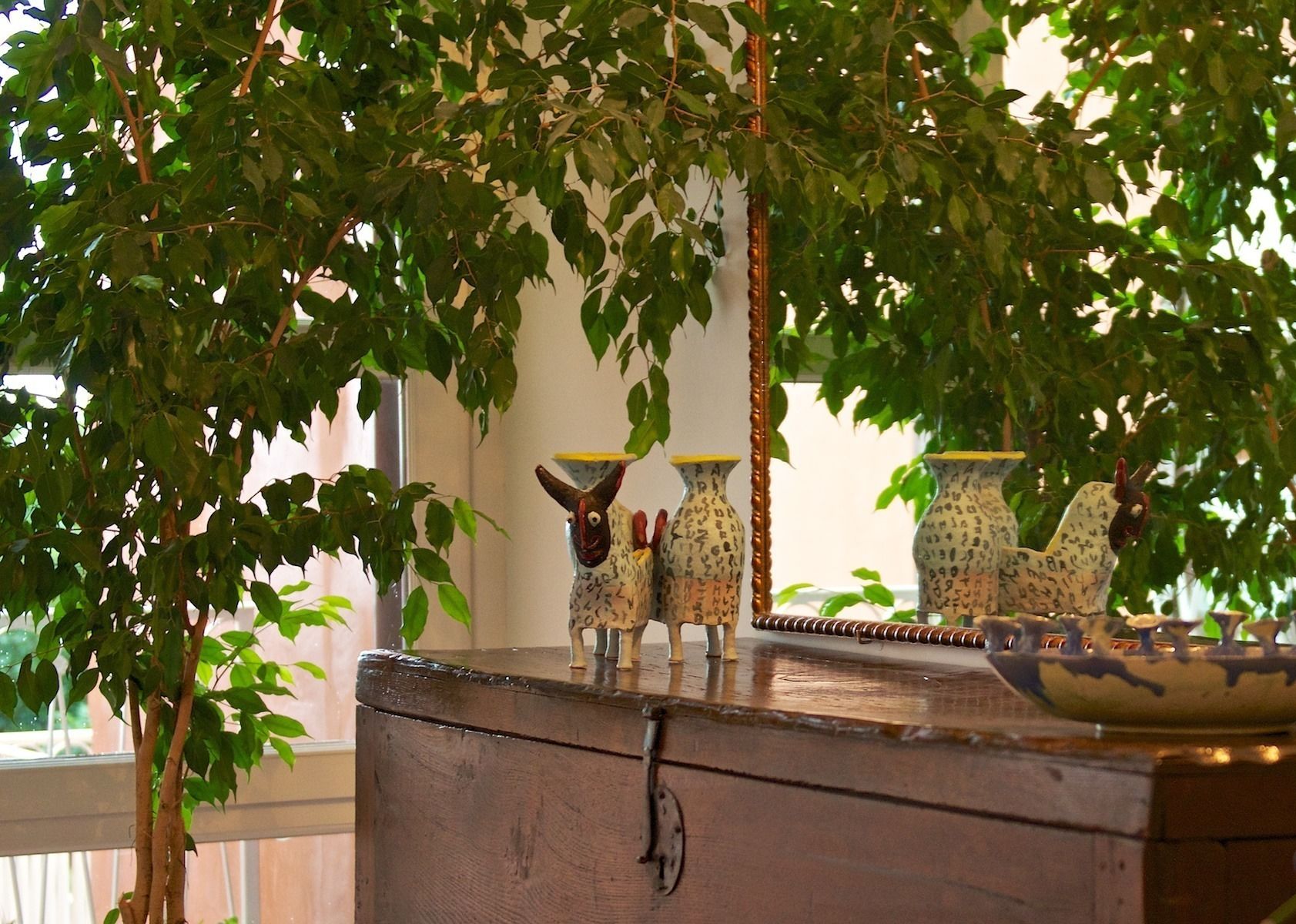 A wooden chest with ceramic animal figurines and vases on top.
