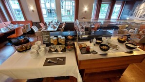 A buffet setup with various food items and condiments, including jars of pickles and a bowl of fruit. - Ratskeller Wiedenbrück (Rheda-Wiedenbruck)