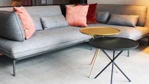 A modern living room with a grey sofa, a round coffee table, and a dark floor lamp. - Ratskeller Wiedenbrück (Rheda-Wiedenbruck)
