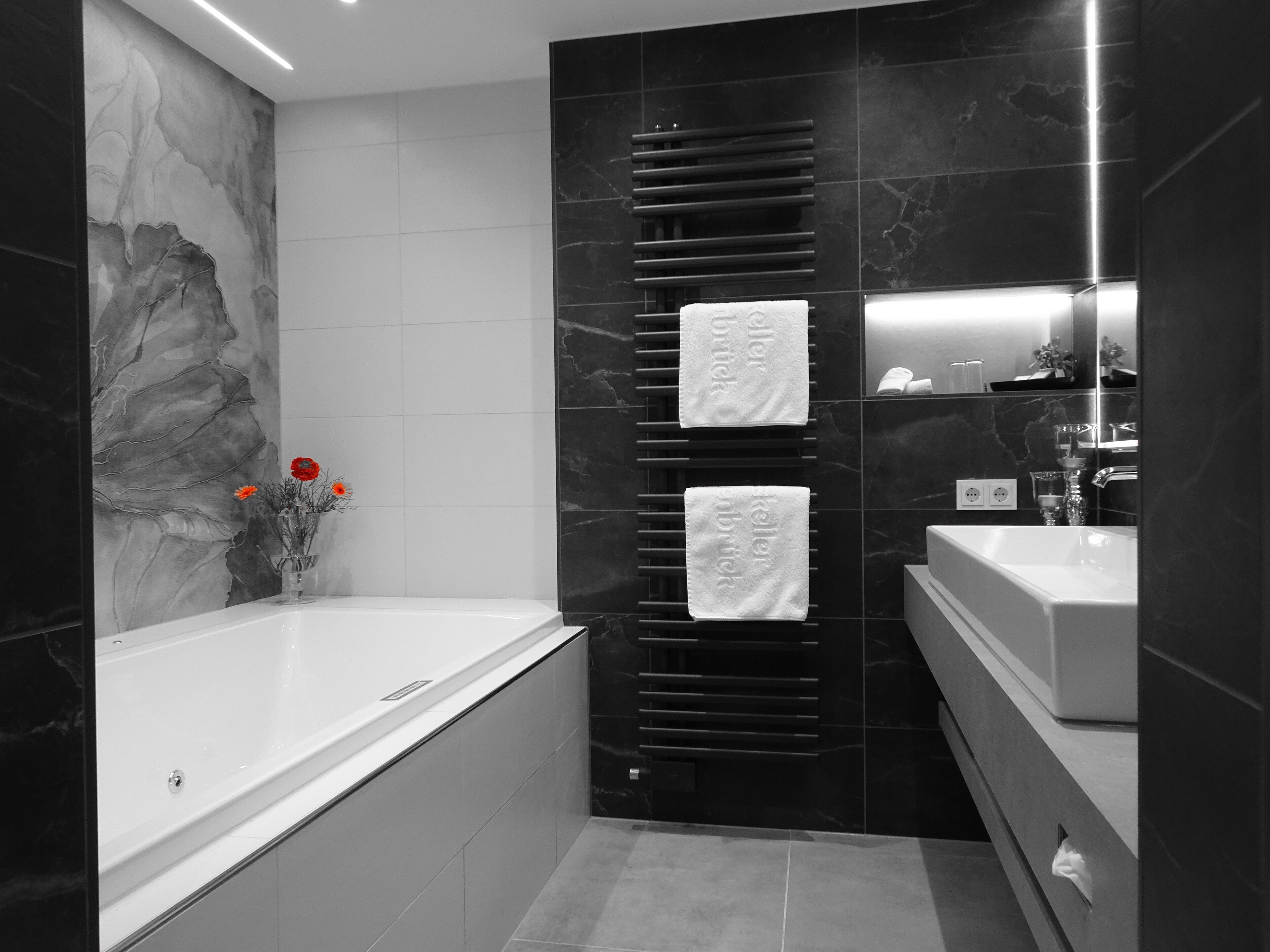 Un baño moderno con bañera, lavabo y perchero para toallas.