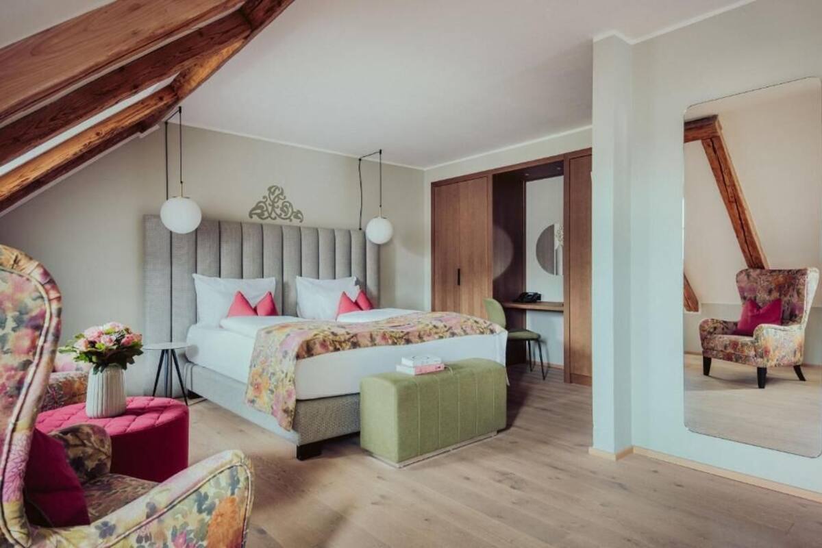 Un dormitorio con una cama grande, un espejo, una silla y una mesita.
