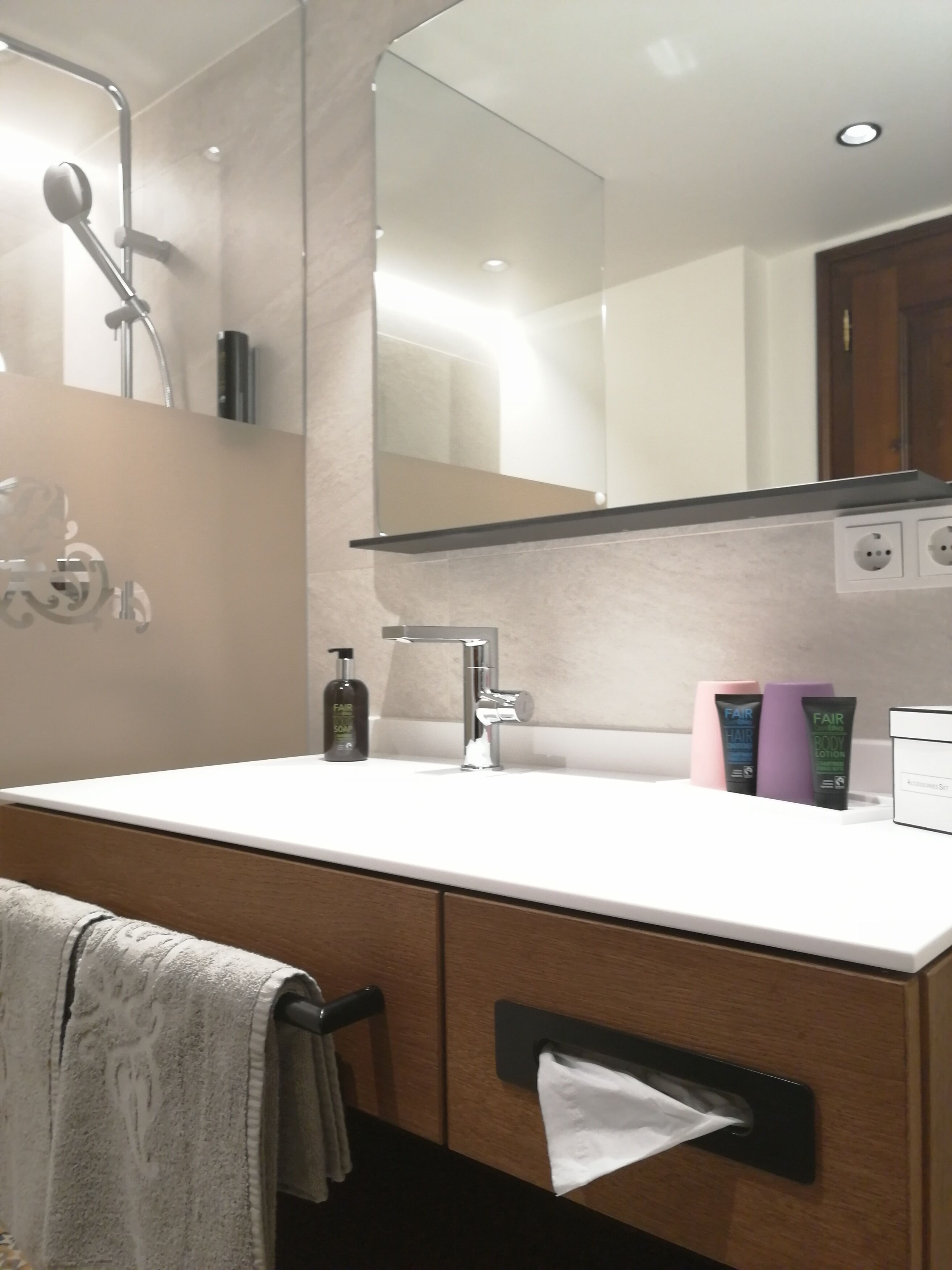 Un baño moderno con un espejo grande, un lavabo y un perchero para toallas.