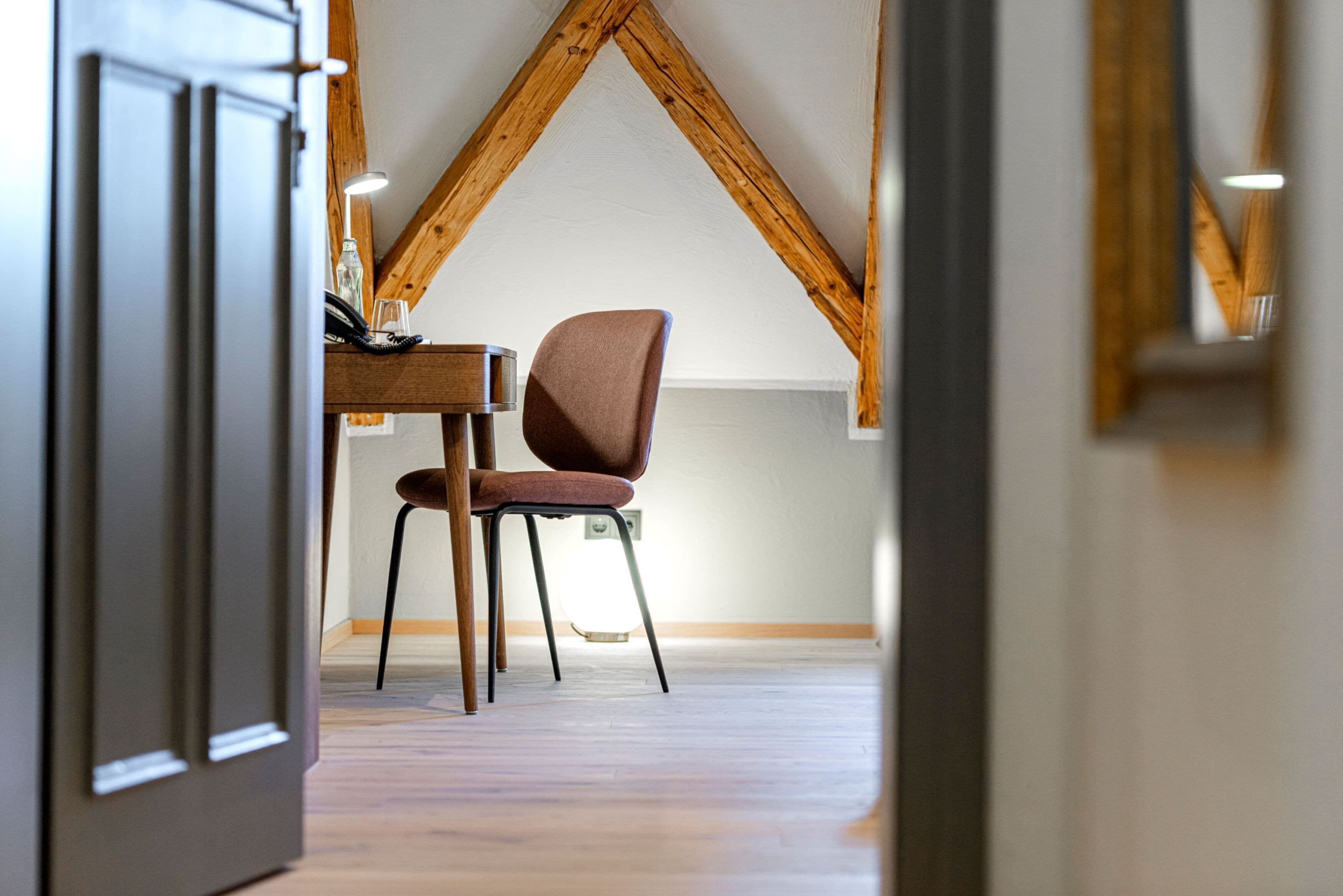 A room with a wooden ceiling, a dining table with chairs, and a visible electrical outlet.