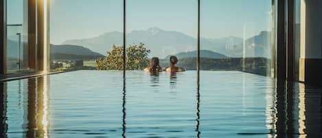 Una piscina techada, una piscina al aire libre, sombrillas