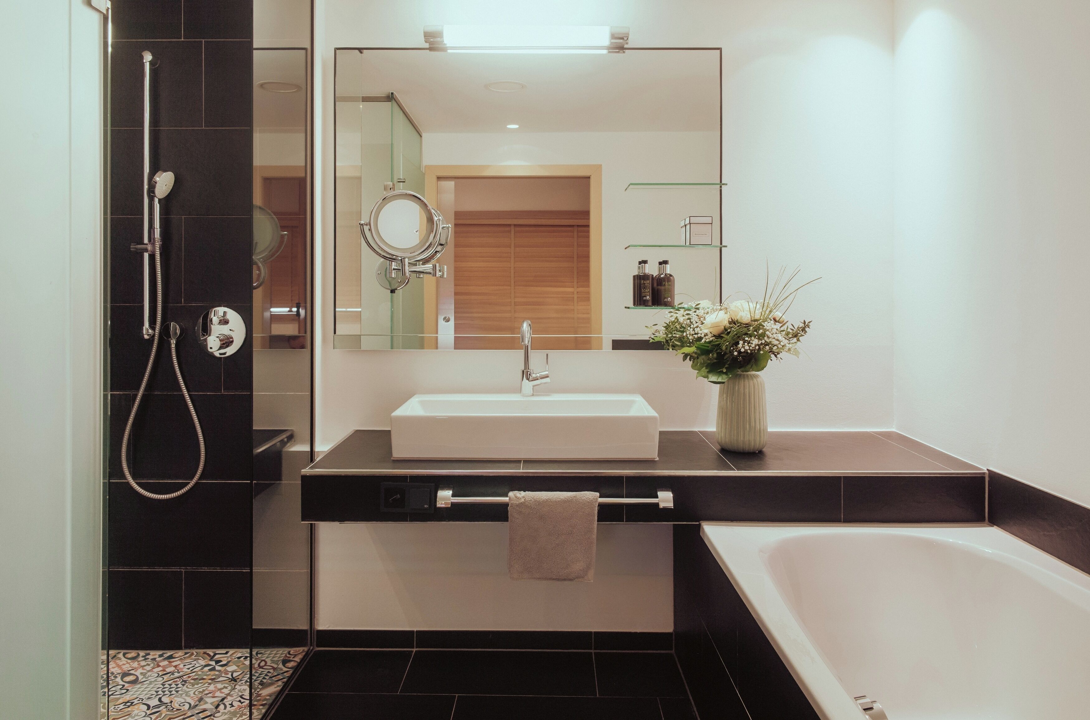 A modern bathroom with a large mirror, a sink, a shower, and a bathtub.