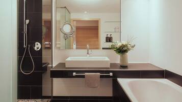 A modern bathroom with a large mirror, a sink, a shower, and a bathtub.