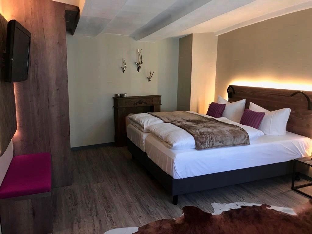 Un dormitorio con una cama grande, cabecera de madera, mesita de noche y decoración en la pared.