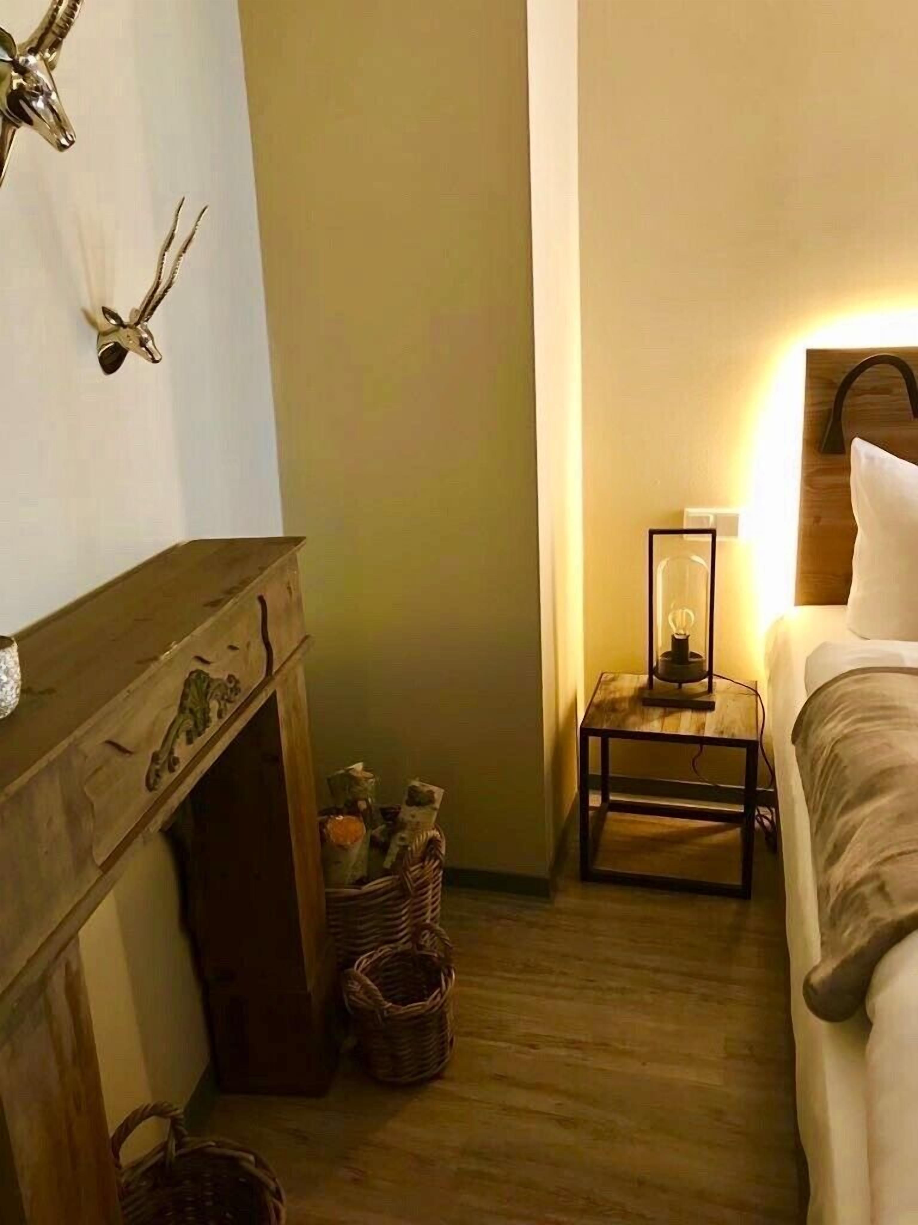 Een gezellige kamer met een open haard, een bed en een nachtkastje met een lamp.