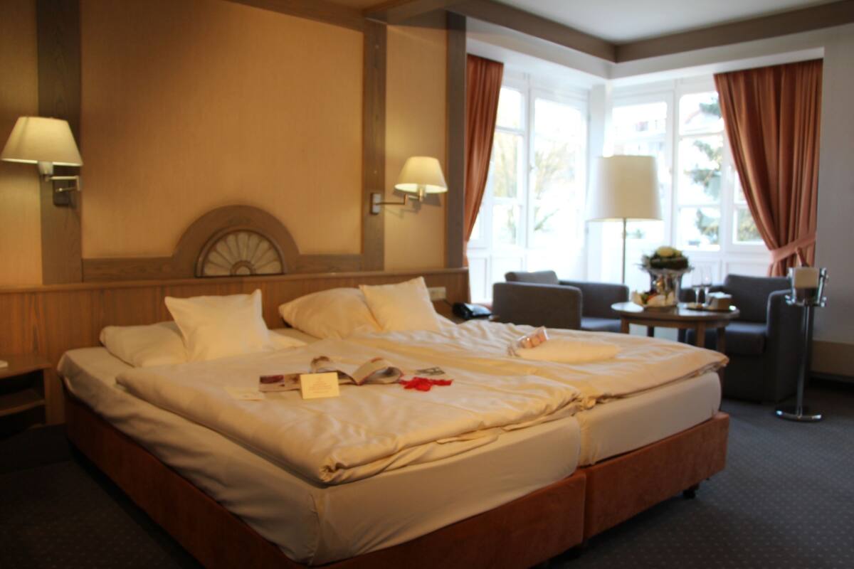 Una habitación de hotel con una cama grande, dos mesitas de noche, un escritorio y una silla.