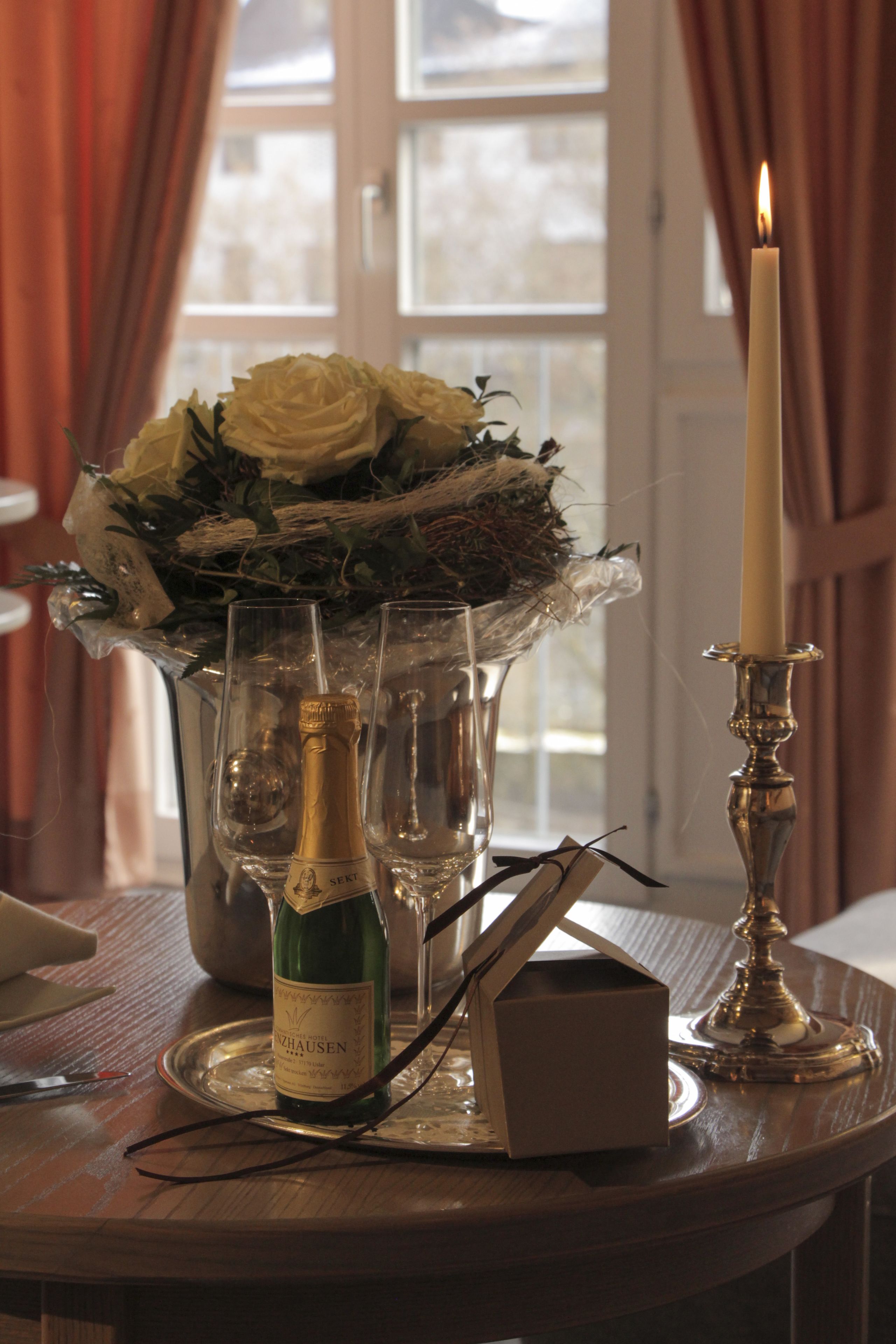 Une table avec une bouteille de vin, des verres, une bougie et un bouquet de fleurs.