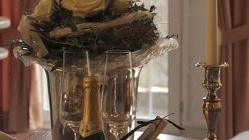 Une table avec une bouteille de vin, des verres, une bougie et un bouquet de fleurs.
