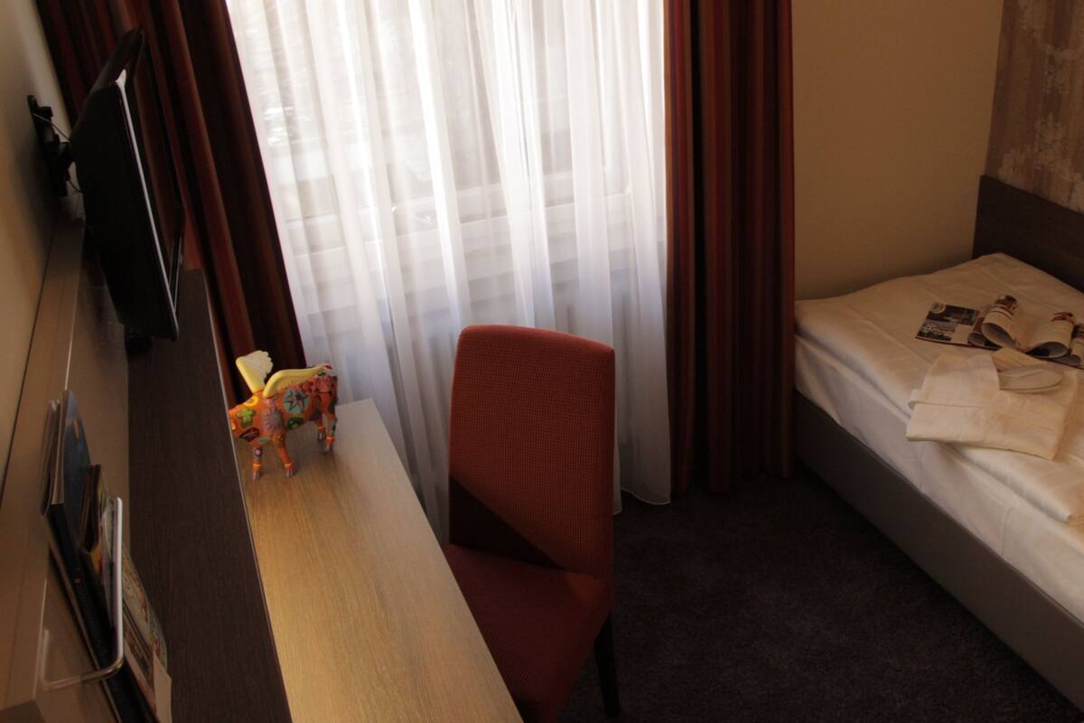 Una habitación de hotel con una cama, un escritorio, una silla y un televisor.