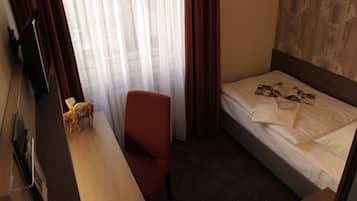 Ett hotellrum med en säng, ett skrivbord, en stol och en tv.