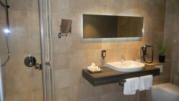 Un baño moderno con cabina de ducha de vidrio, un lavabo con espejo y un inodoro.